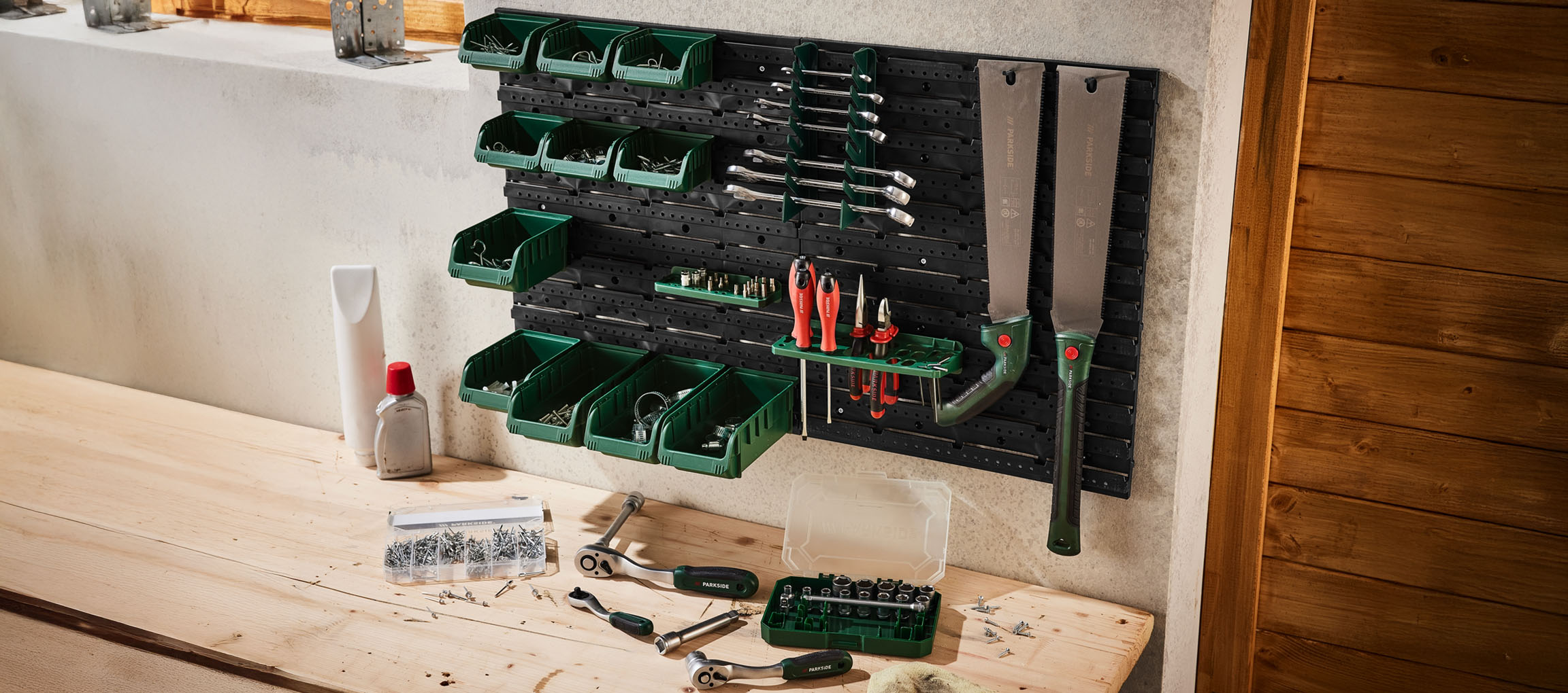 Parkside sienas stiprināms instrumentu organizators ar dažādiem instrumentiem un uzglabāšanas kastes.