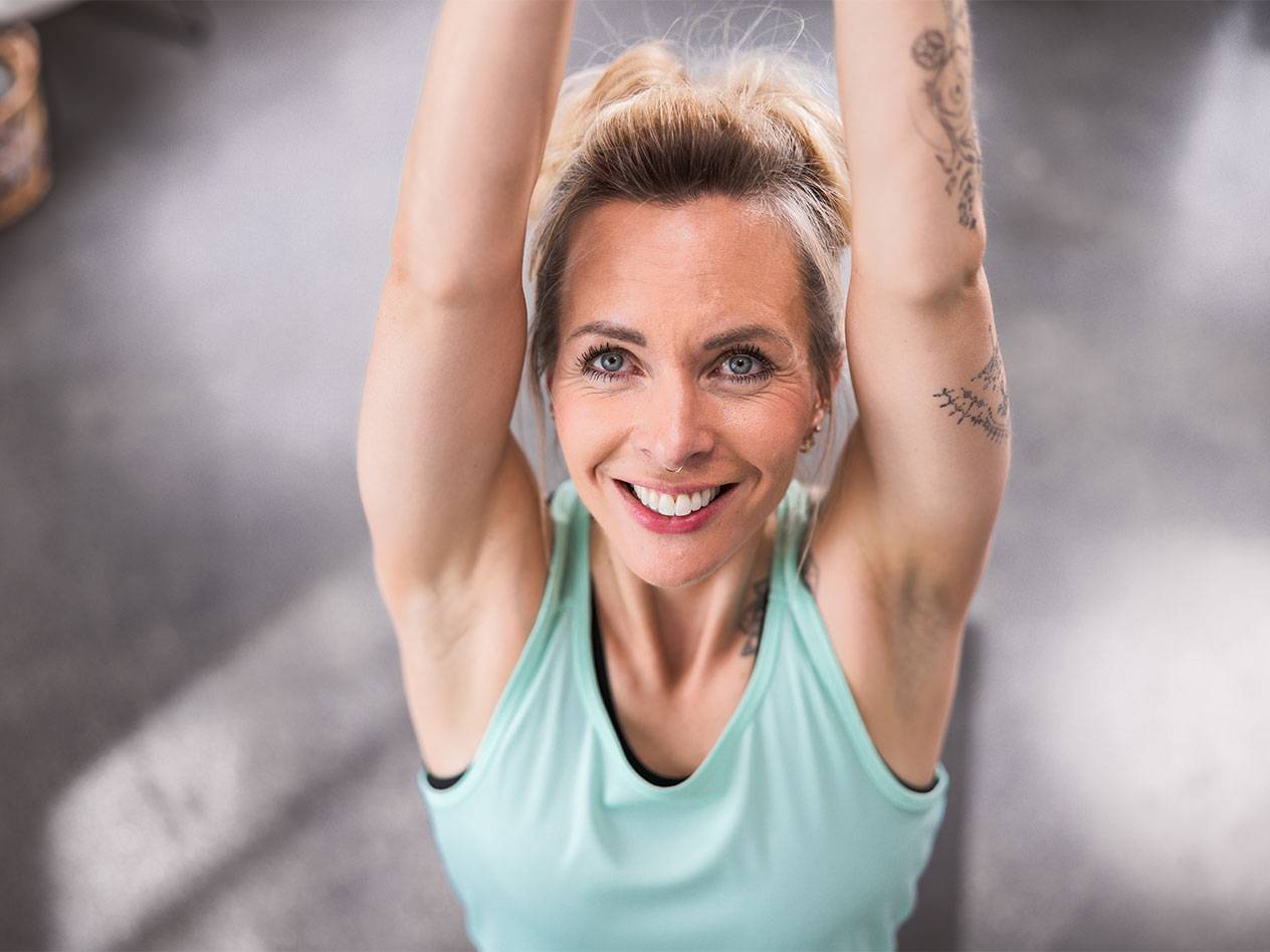 Блондинка в голубой майке улыбается в камеру.