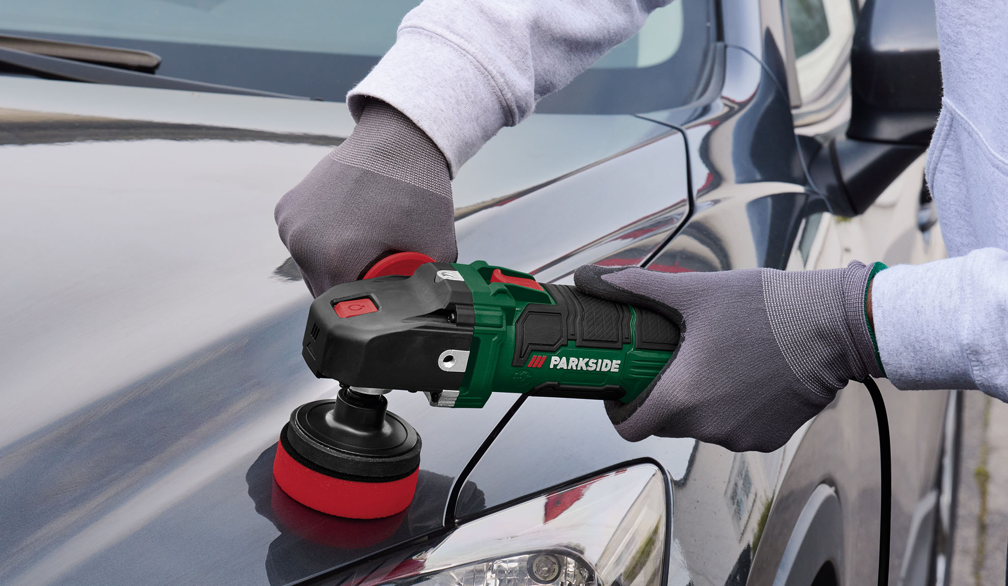 Persona pulē automašīnas motora pārsegu ar Parkside pulētāju.