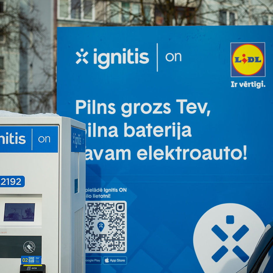Elektrouzlādes stacija pie veikala, piedāvājot pilnu uzlādi elektromobilim.