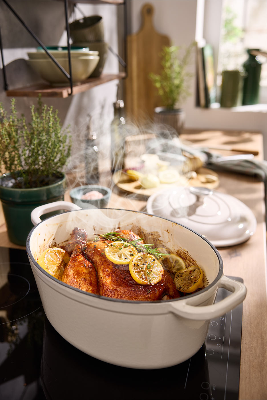 Cepta vista ar citroniem un rozmarīnu ovālā čuguna katlā uz plīts virsmas.