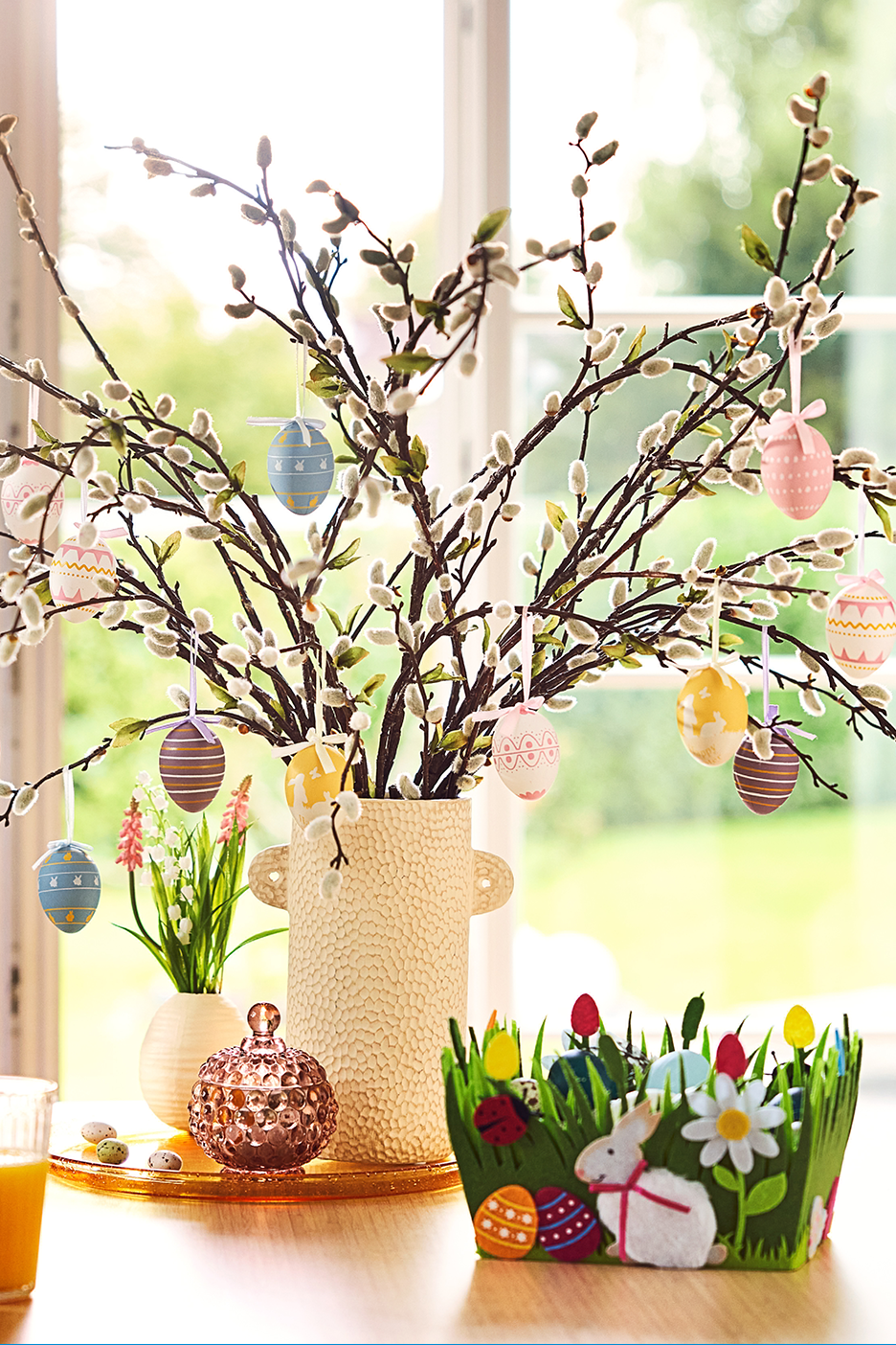Lieldienu rotājumi: vāze ar pūpoliem un dekoratīvām olām, grozs ar zaķi un olām.