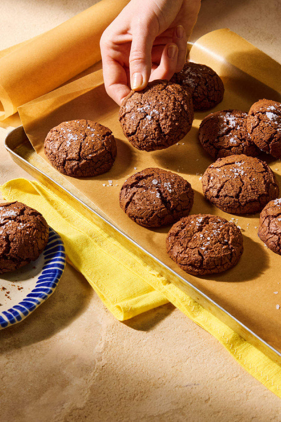 Šokolādes cepumi ar jūras sāli uz cepamās paplātes ar cepamo papīru.