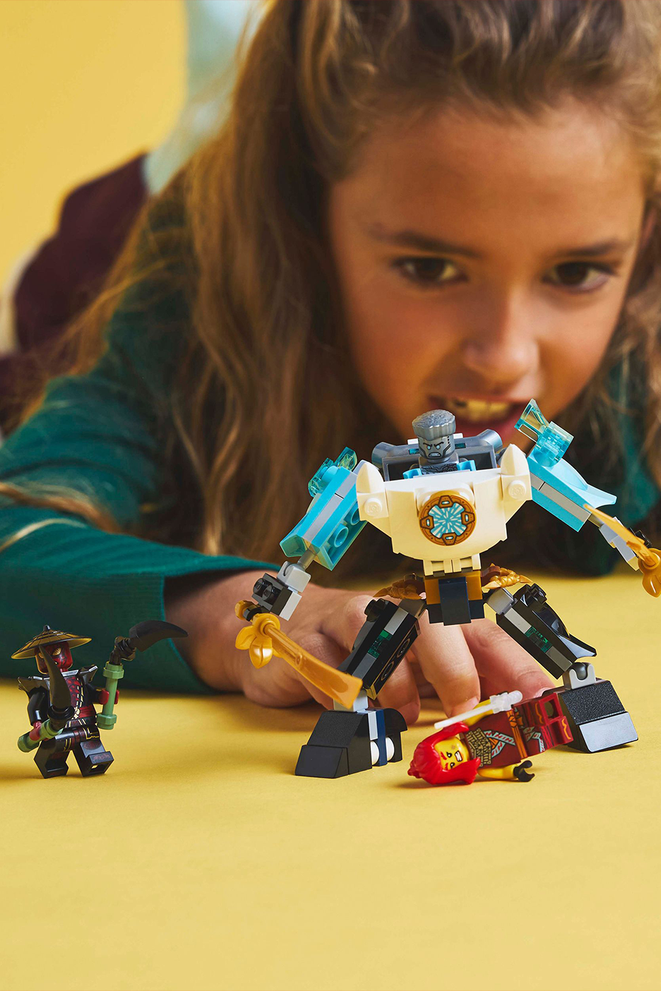 Meitene spēlējas ar rotaļu figūriņām un robotu uz dzeltena fona.