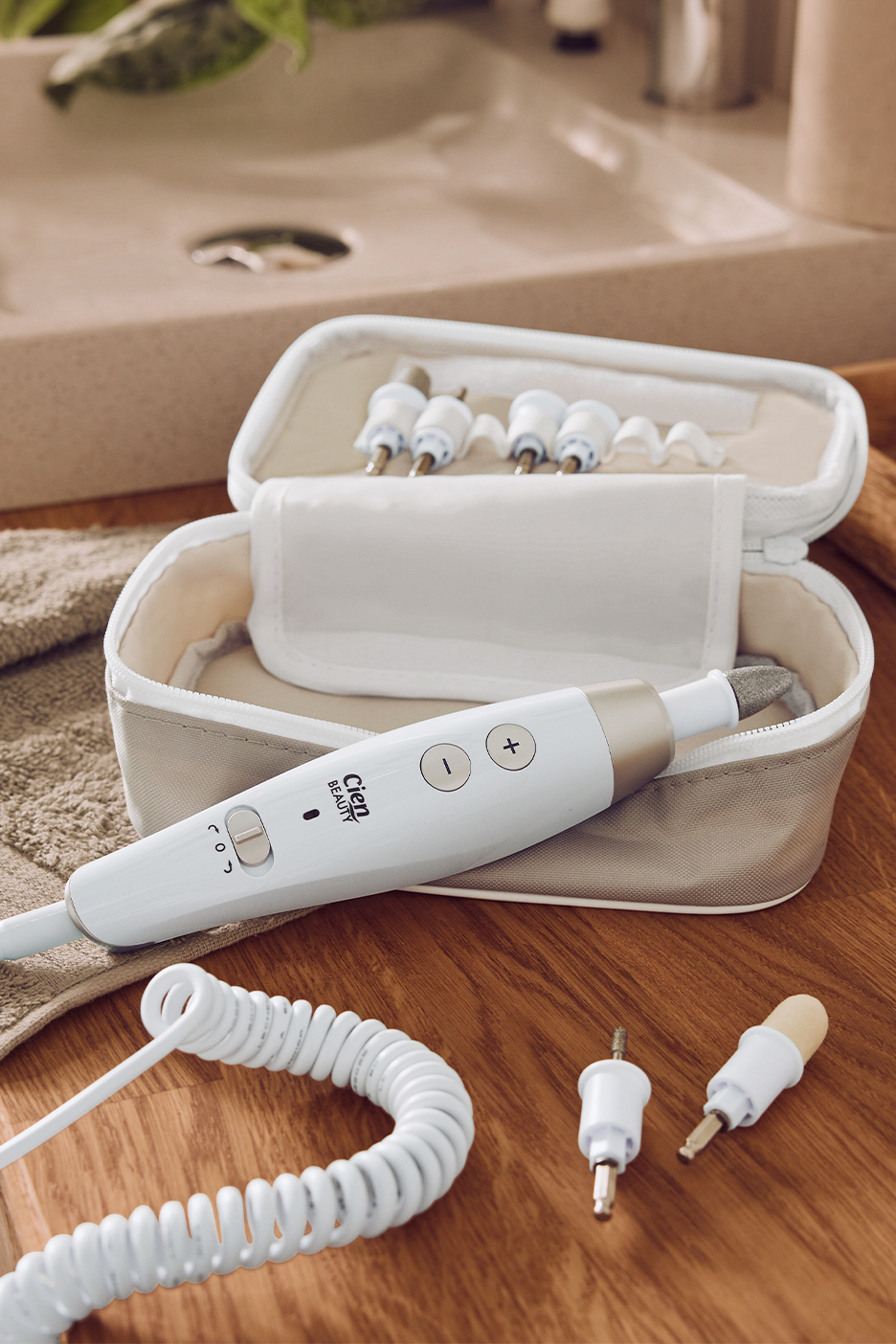 Набор для маникюра и педикюра Cien Beauty с насадками и футляром на деревянном столе.