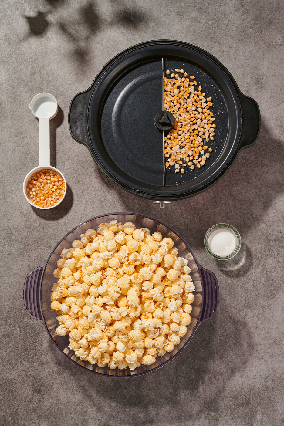 Popkorns, kukurūzas graudi mērkarotē un popkorna gatavošanas ierīcē, un sāls.