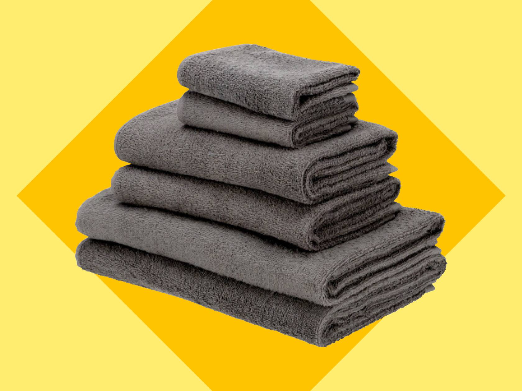 Стопка серых полотенец разного размера на желто-оранжевом фоне.