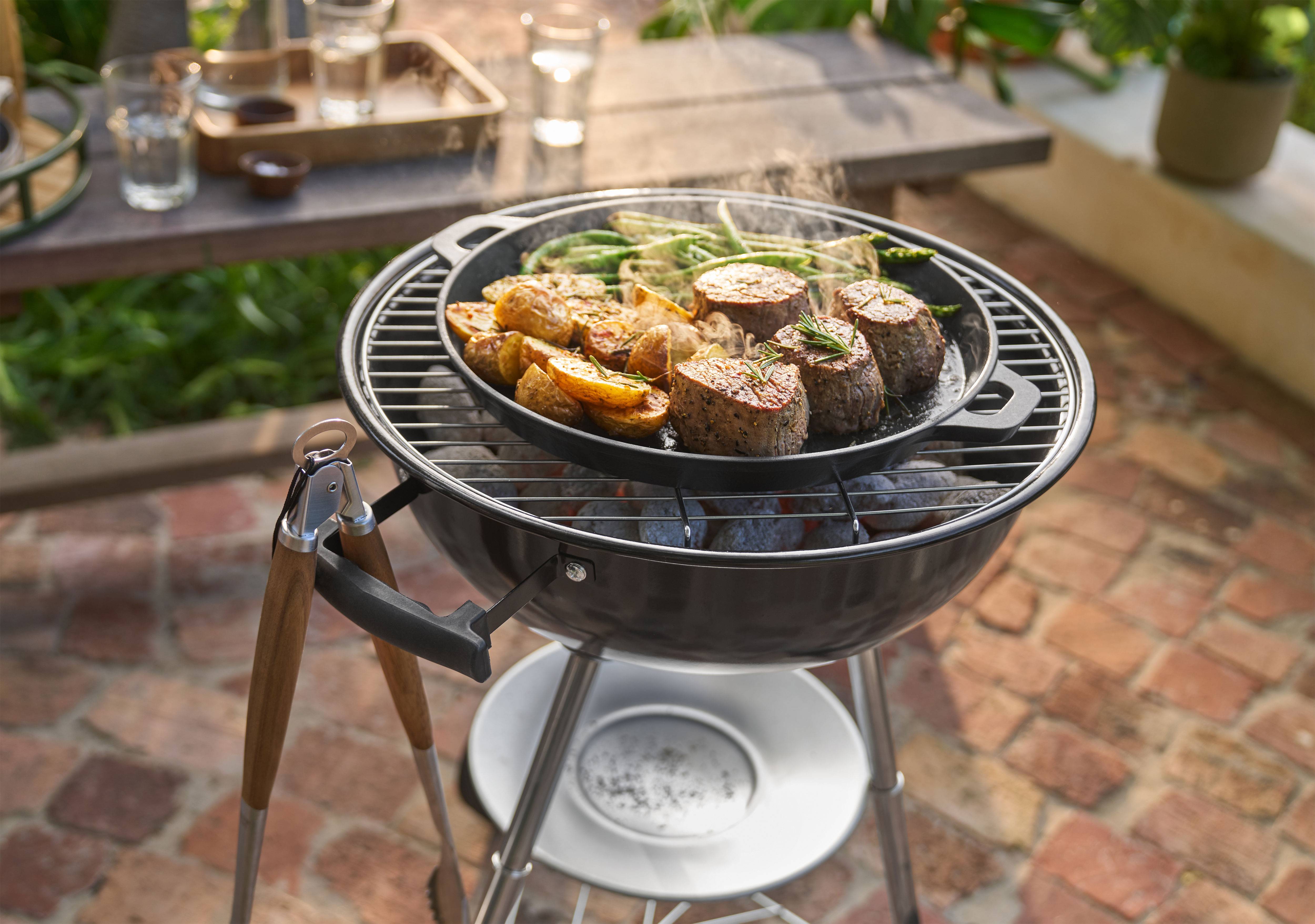 Барбекю с мясом, картофелем и зеленой фасолью, готовящимися на сковороде на улице.