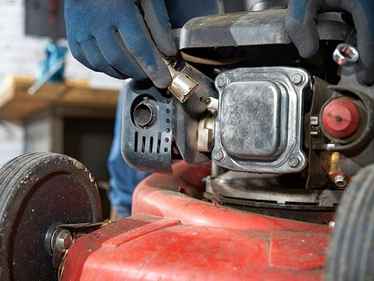 Cimdiem apvilktas rokas maina aizdedzes sveci sarkanā zāles pļāvējam.