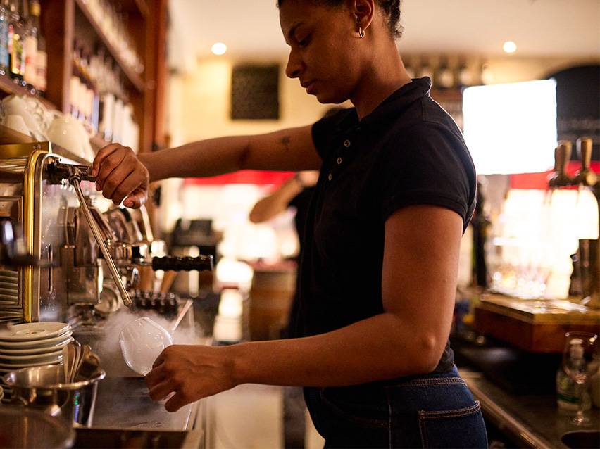 Barista gatavo dzērienu ar tvaiku no kafijas automāta.