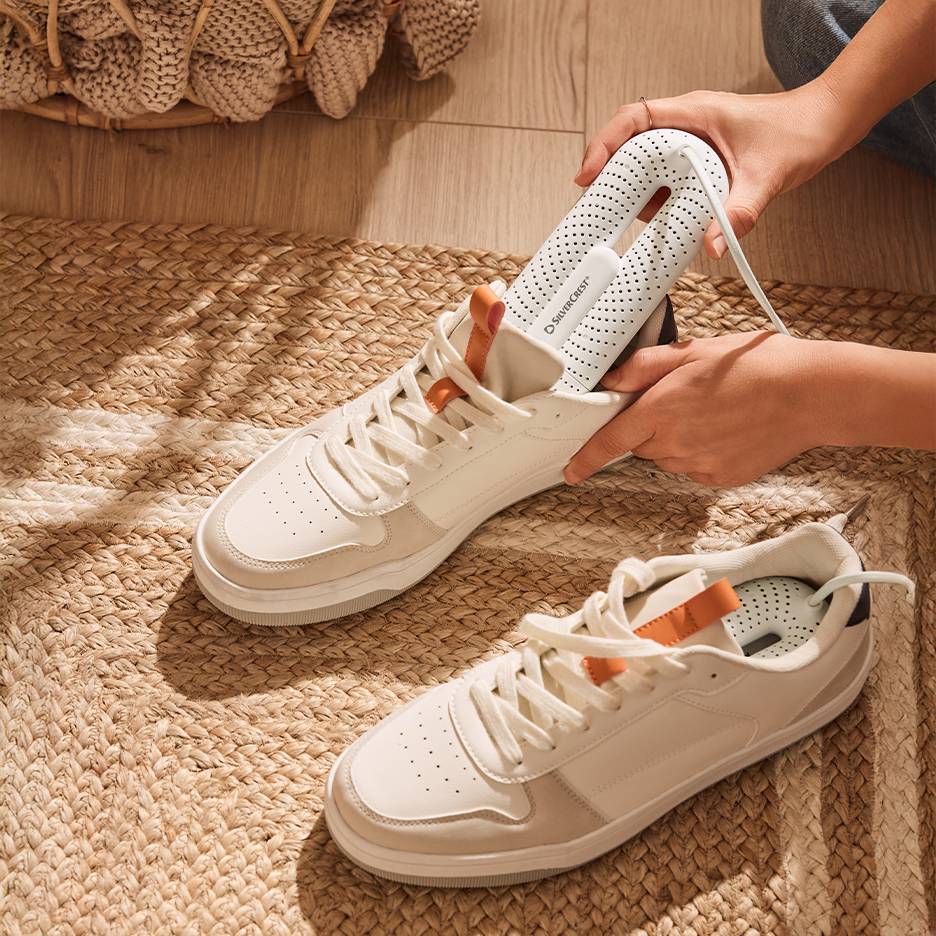 Сушилка для обуви Silvercrest в белых кроссовках на плетеном коврике.