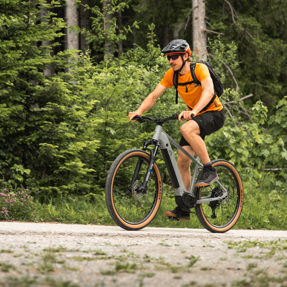 Vīrietis brauc ar elektrisko velosipēdu meža takā.