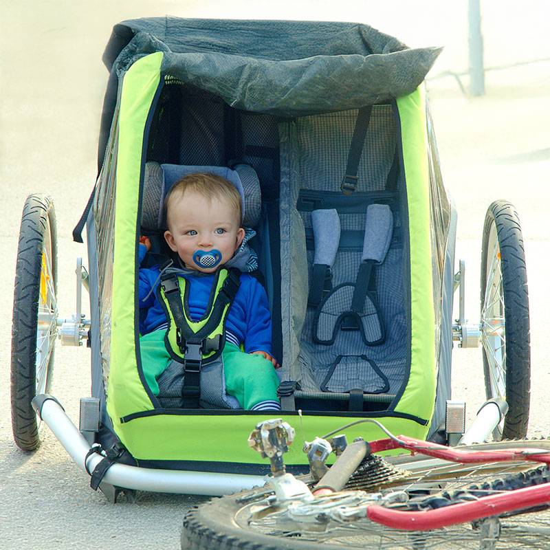Zīdainis velosipēda piekabē.