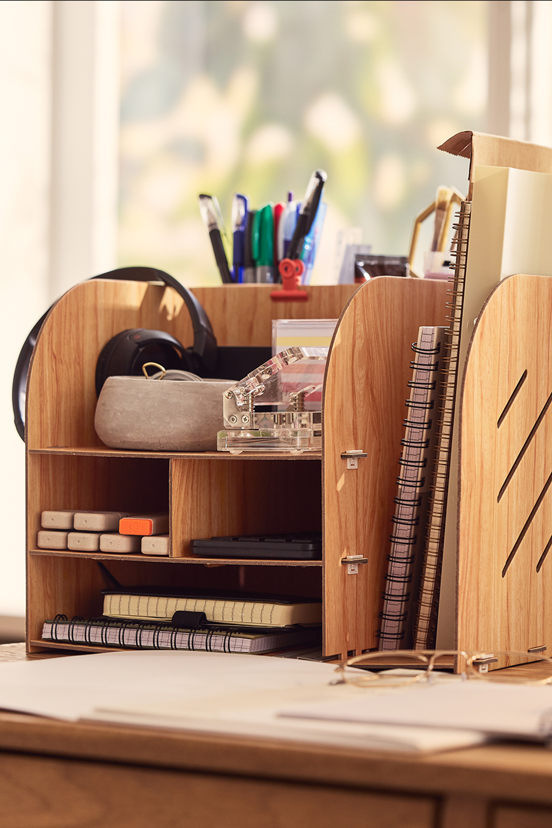 Koka galda organizators ar pildspalvām, piezīmju grāmatiņām un citiem biroja piederumiem.