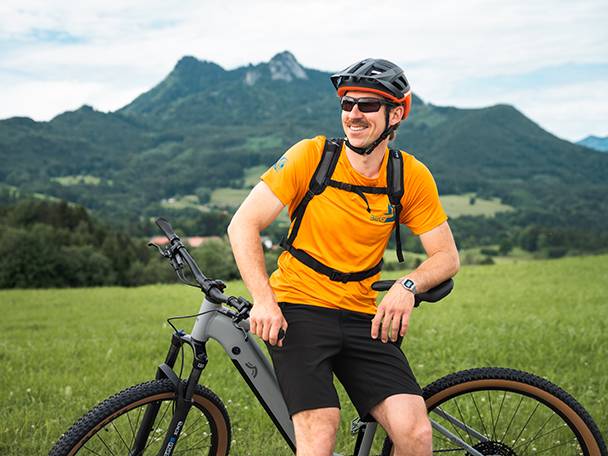 Elektriskais velosipēds un velosipēdists kalnu ainavā.