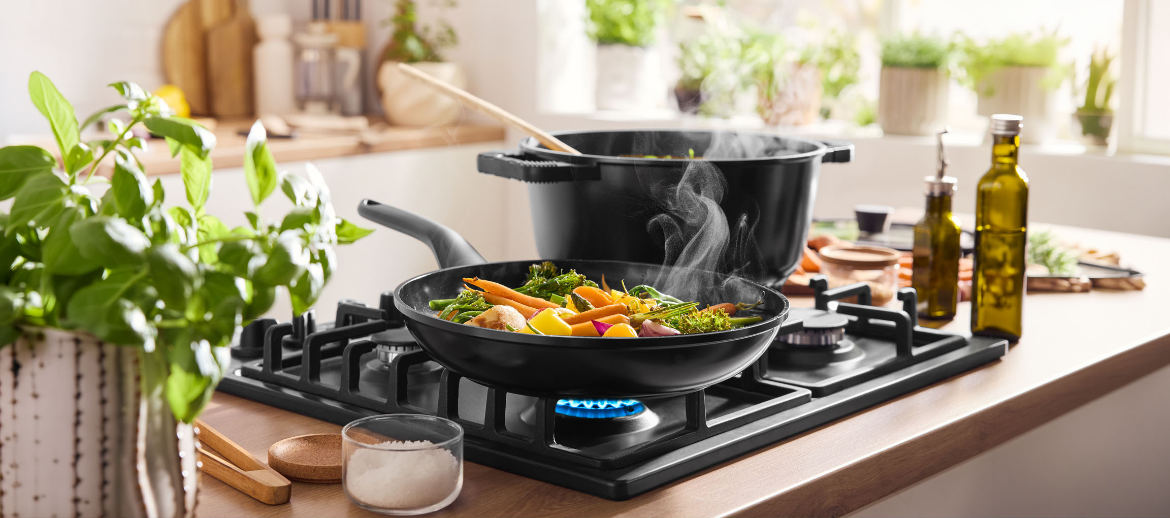 Приготовление овощей на сковороде на газовой плите, рядом кастрюля и оливковое масло.