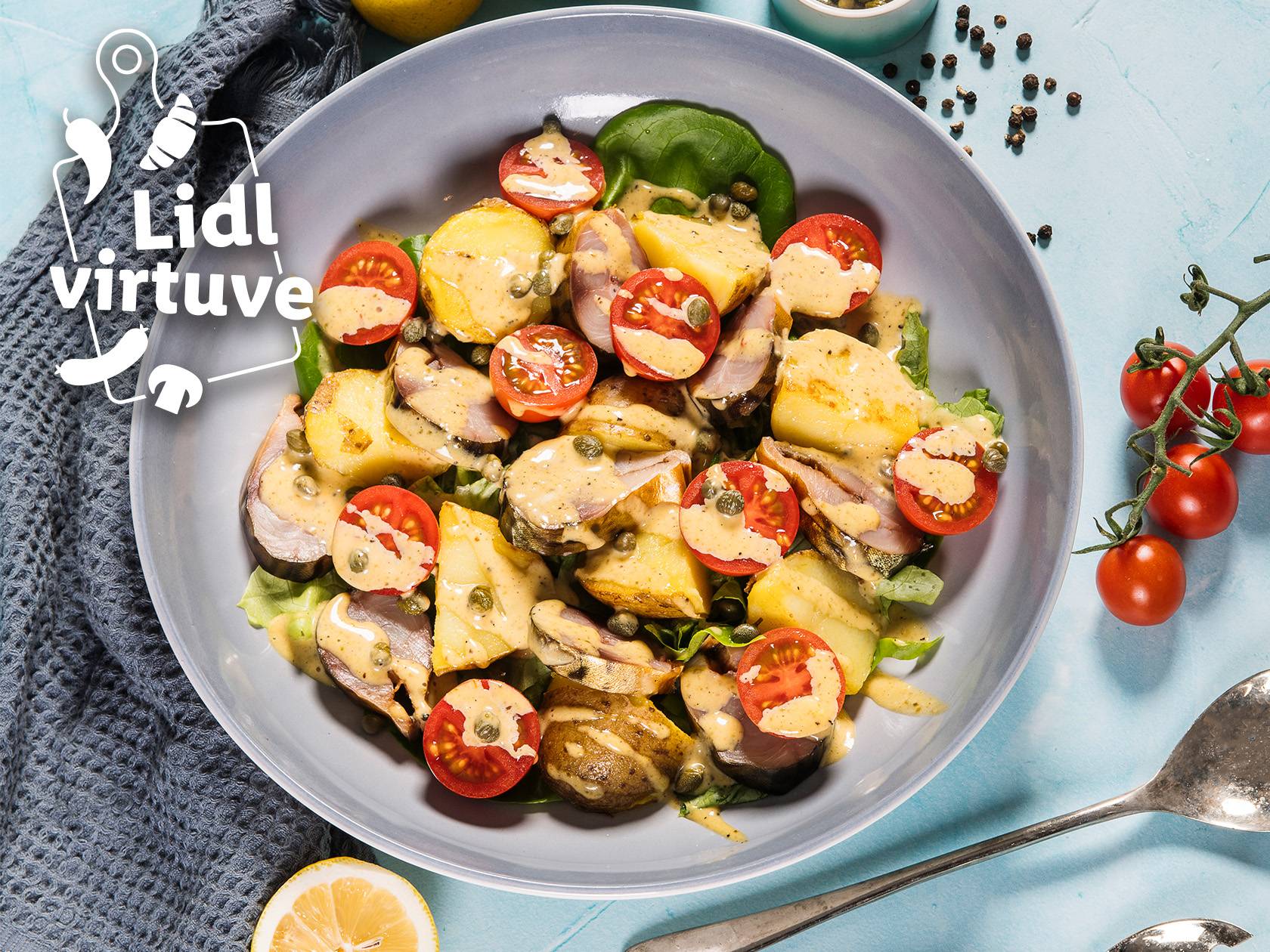Lidl virtuve: salāti ar kartupeļiem, tomātiem, zivi un mērci pelēkā bļodā.