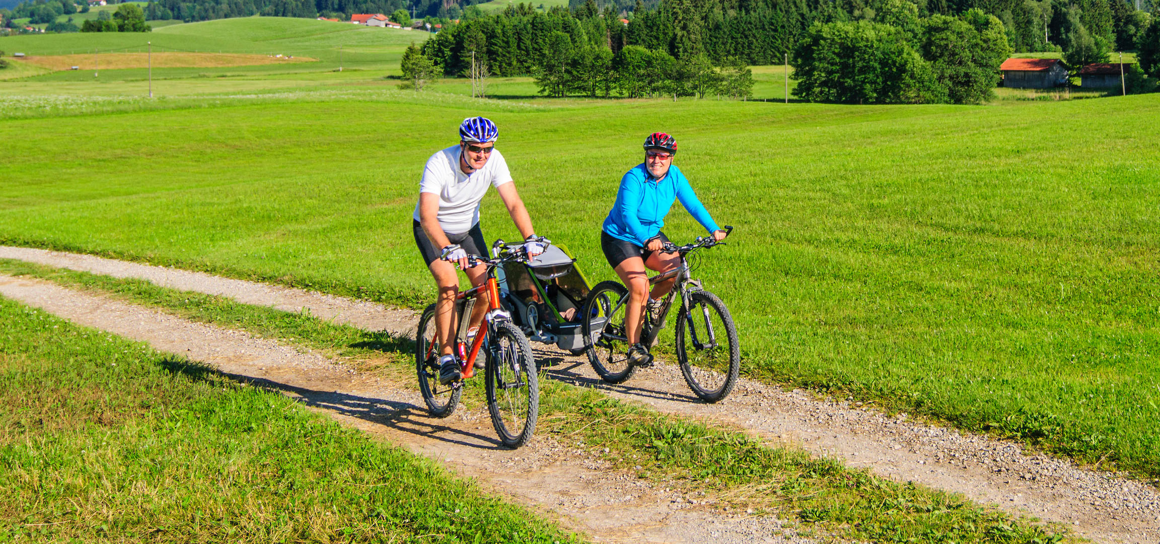 Pāris brauc ar velosipēdiem zaļā ainavā.
