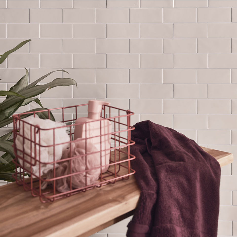 Декор ванной комнаты с белой плиткой, деревянной скамьей, корзиной с мылом и полотенцами.