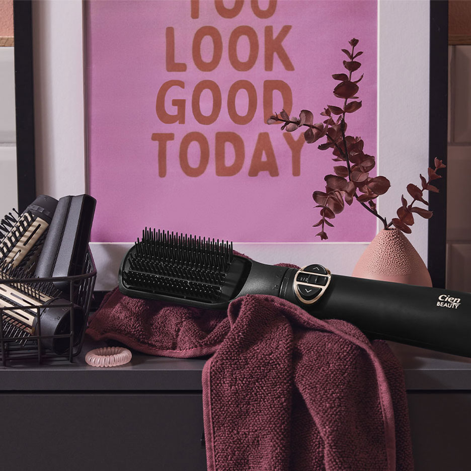 Выпрямляющая щетка Cien Beauty на полотенце, с аксессуарами для волос и плакатом.