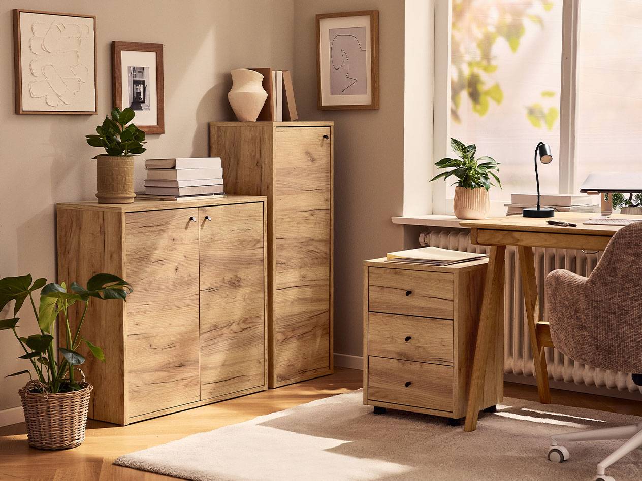 Домашний офис со светлыми деревянными шкафами, офисным креслом и настольной лампой.