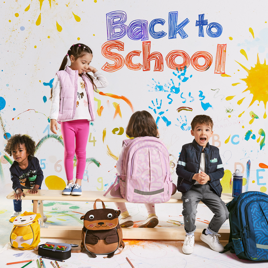 Četri bērni ar mugursomām un skolas piederumiem, ar tekstu „Back to School“ uz krāsaina fona.