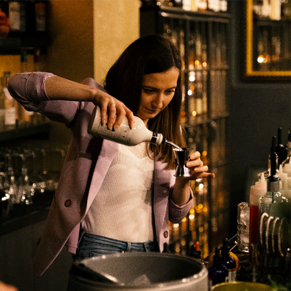 Bārmeniete lej alkoholu jiggerā.