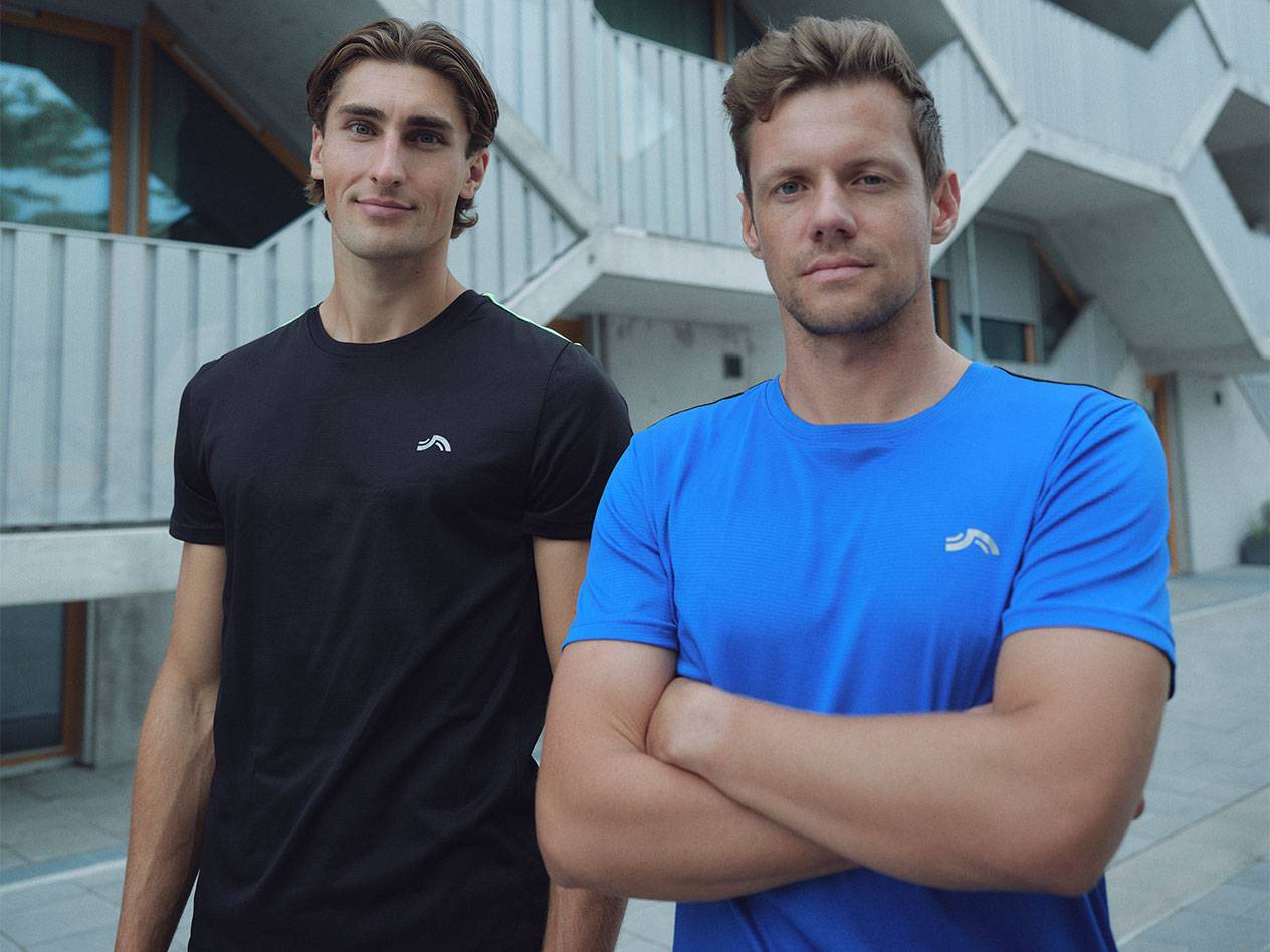 Двое мужчин в черных и синих спортивных футболках с логотипом.