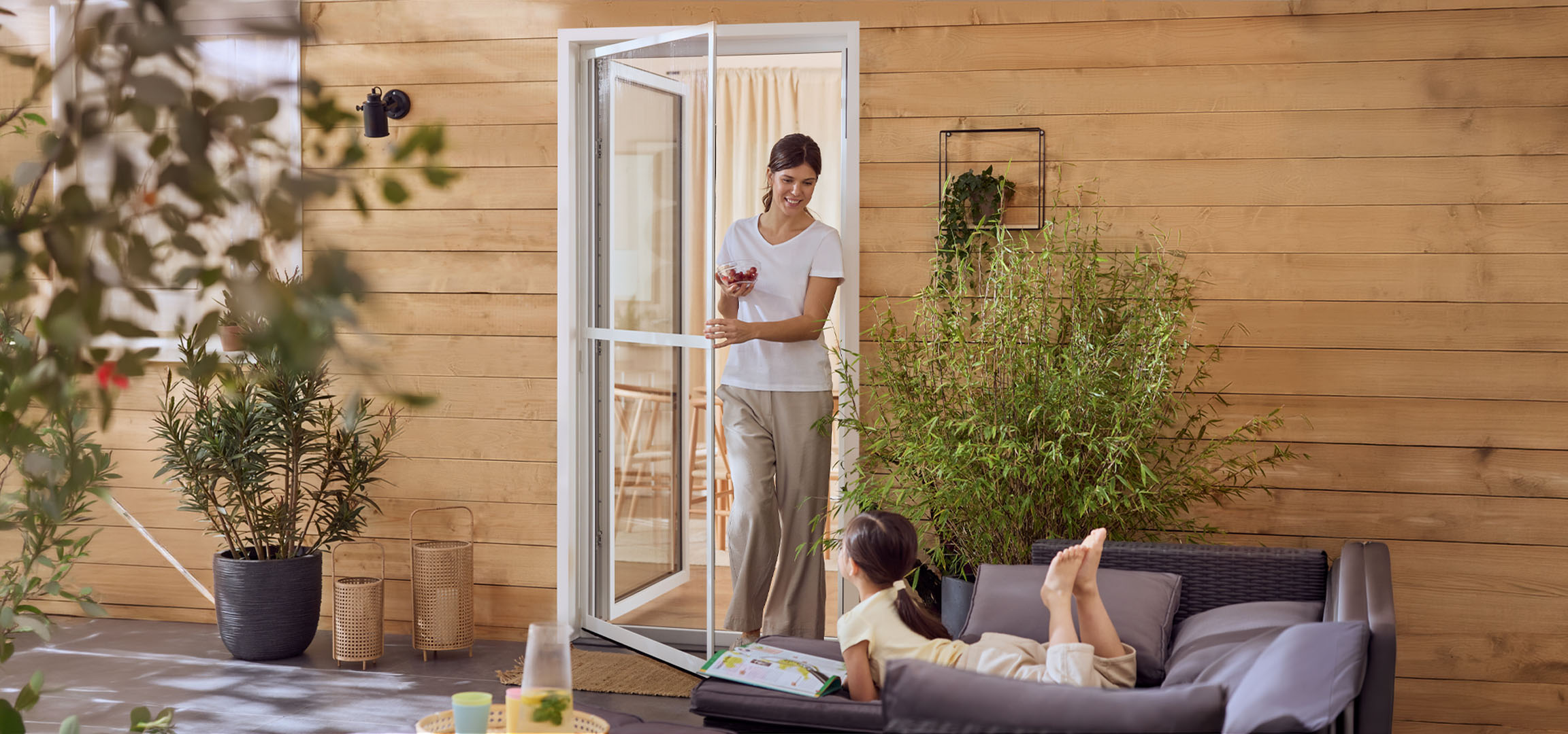 Женщина и девочка наслаждаются патио с уличной мебелью и растениями.