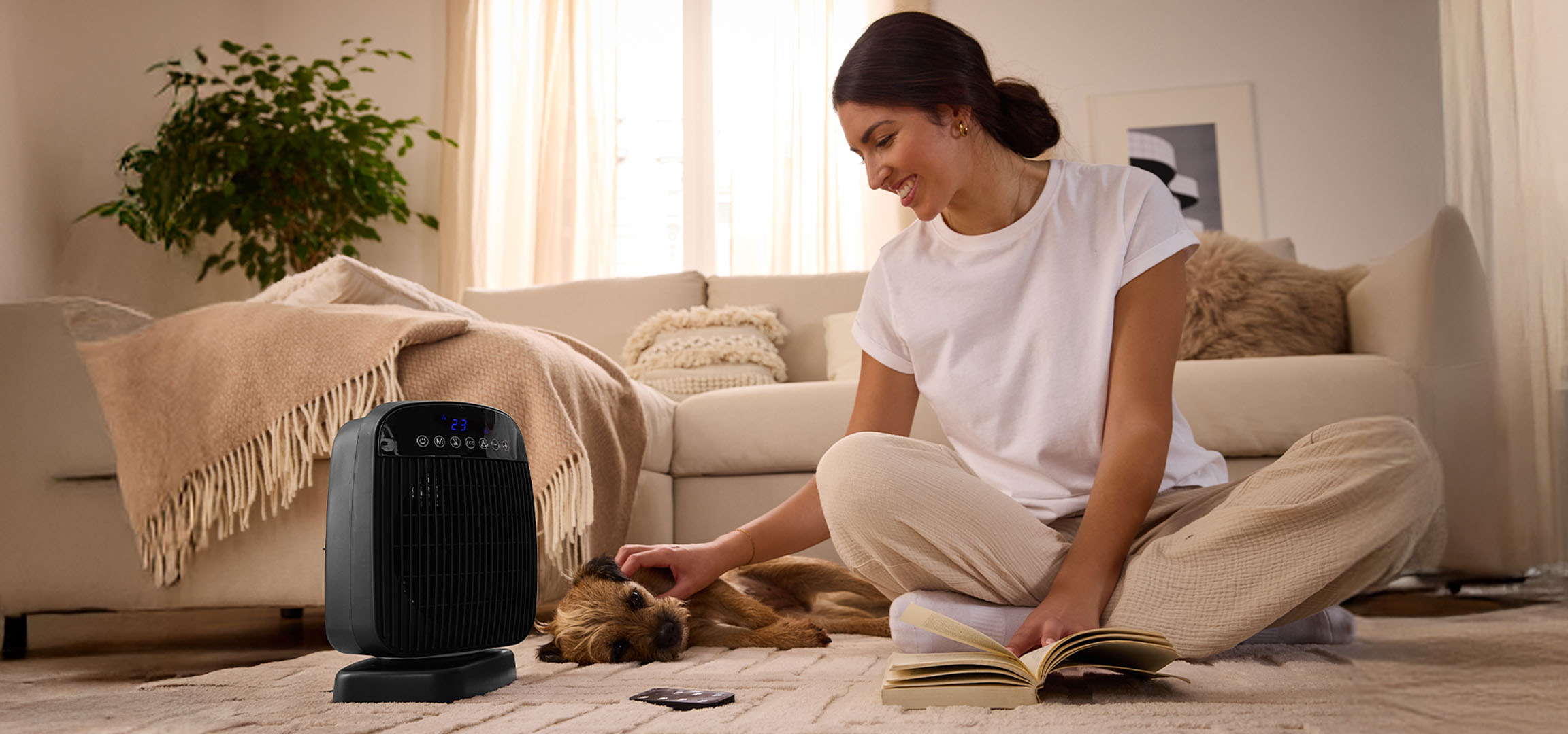 Женщина играет с собакой рядом с электрическим обогревателем в гостиной.