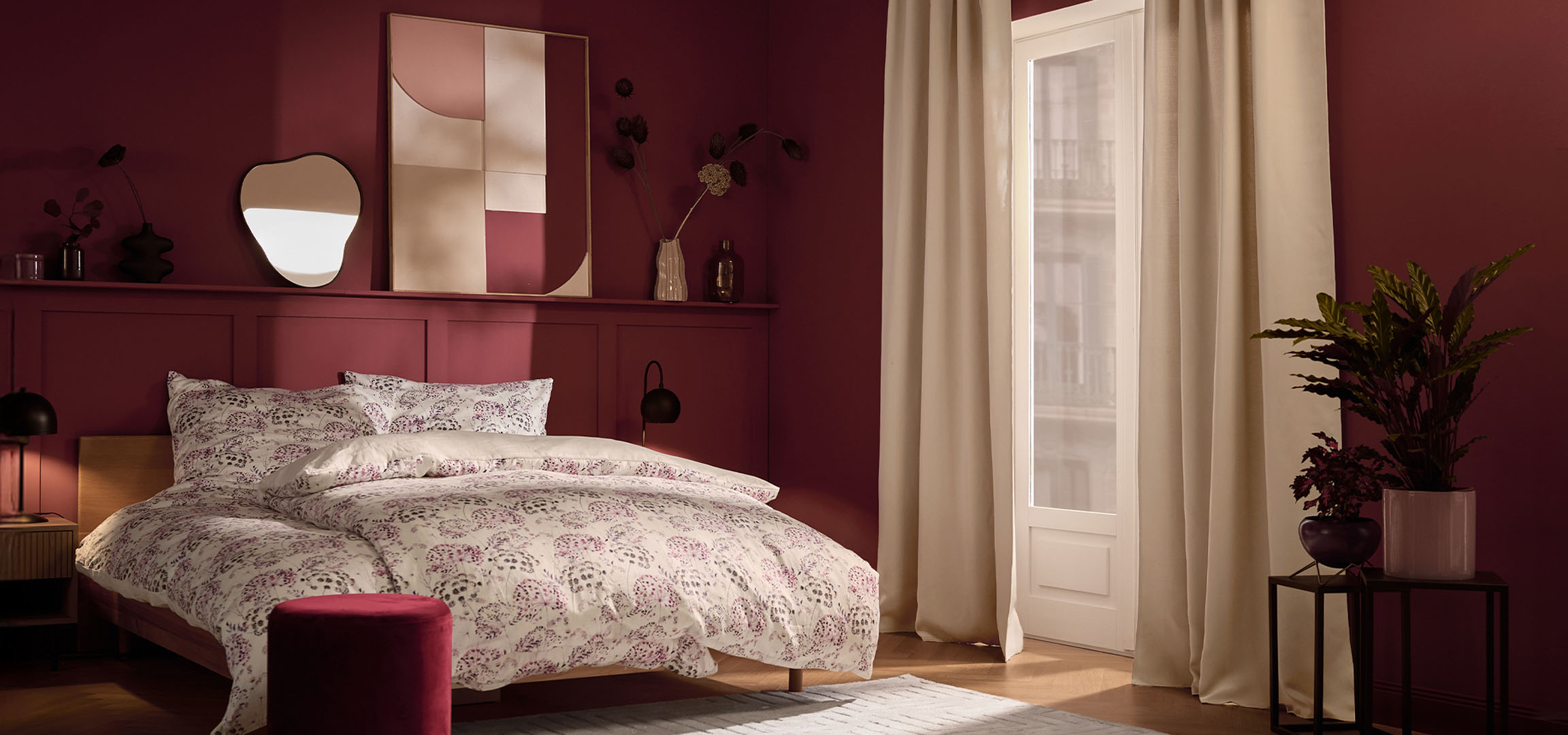 Спальня с бордовыми стенами, кроватью с белым постельным бельем с цветочным узором и растениями.