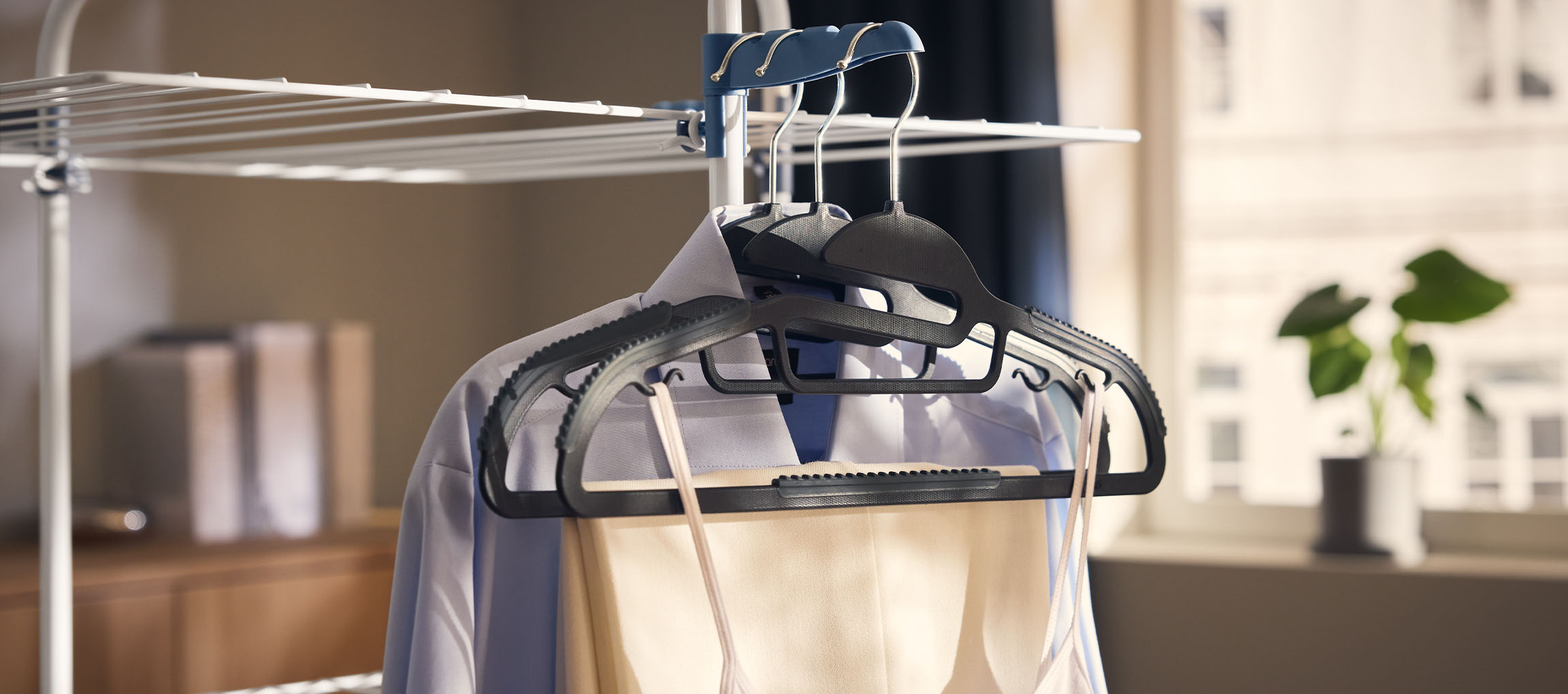 Drēbes uz pakaramajiem uz veļas žāvētāja, ar augu fonā.