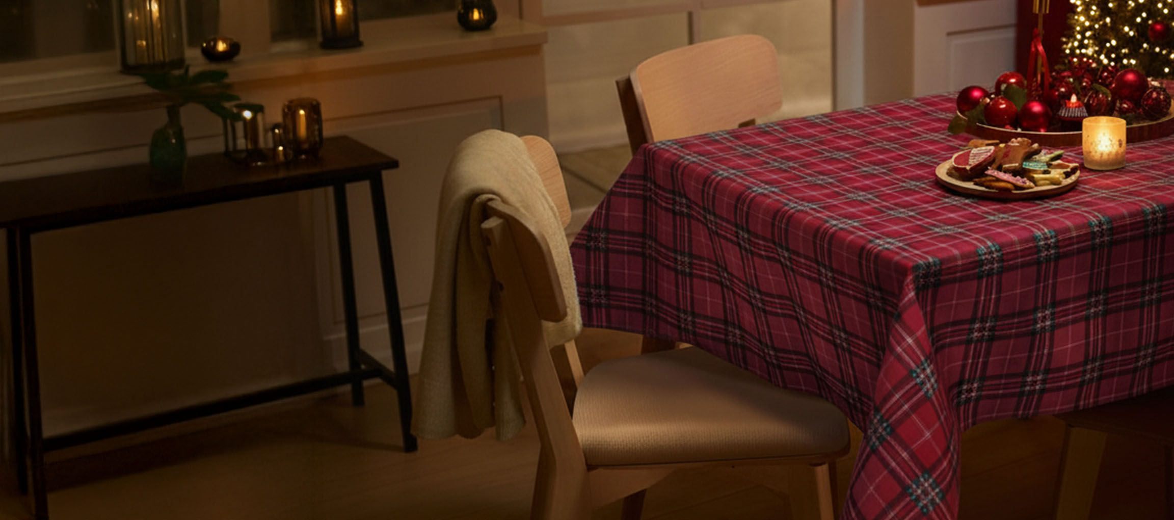 Рождественская сервировка стола с красной клетчатой скатертью, стульями и рождественским печеньем.