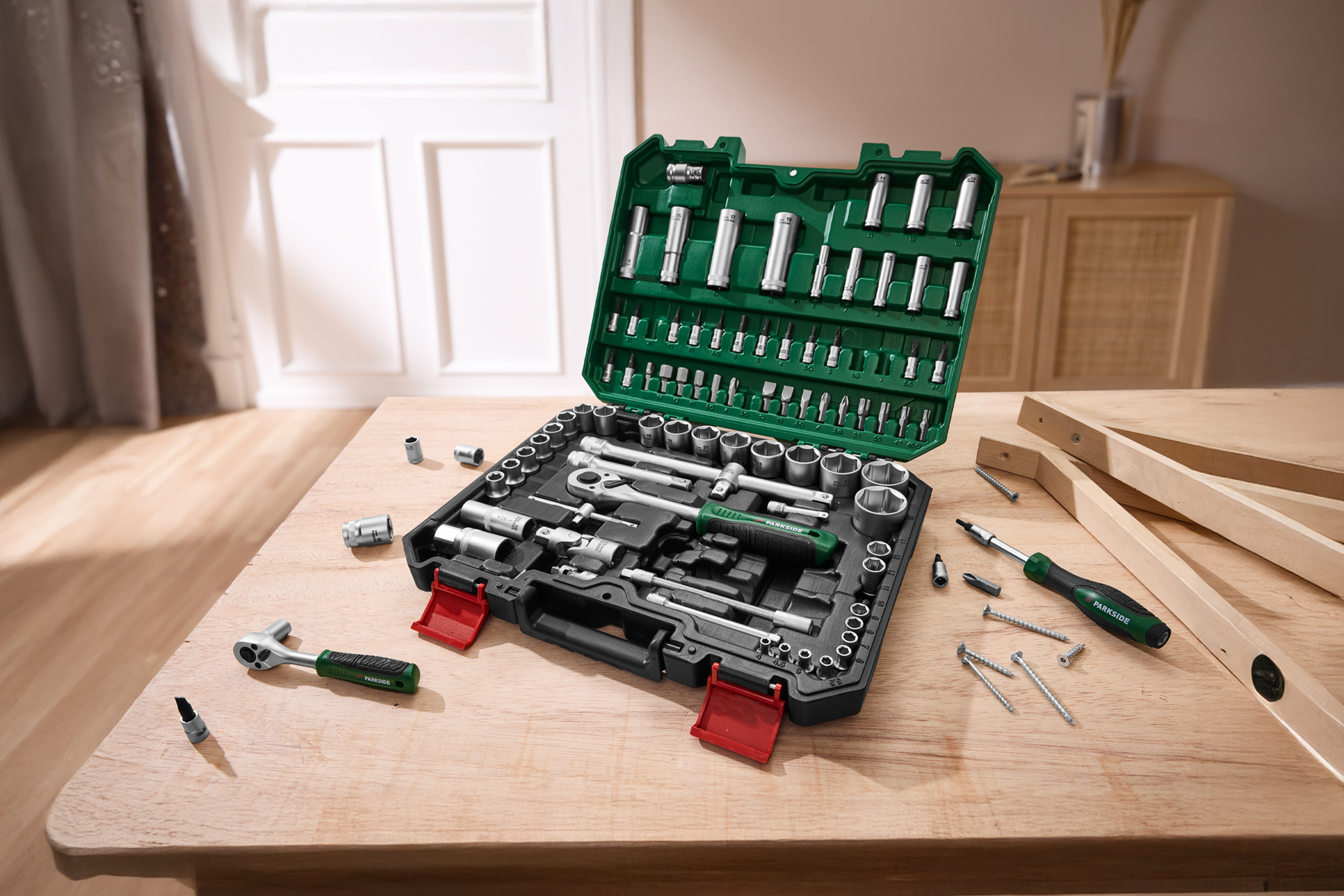 PARKSIDE instrumentu komplekts ar uzgriežņu atslēgām, skrūvgriežiem un uzgaļiem uz koka galda.