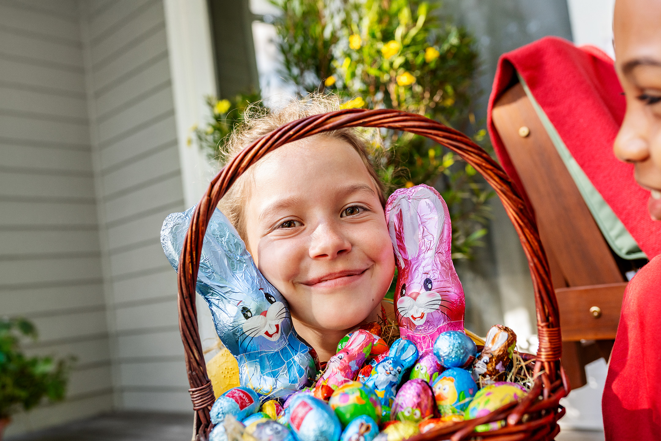 Meitene ar Lieldienu grozu, pilnu ar šokolādes zaķiem un olām.