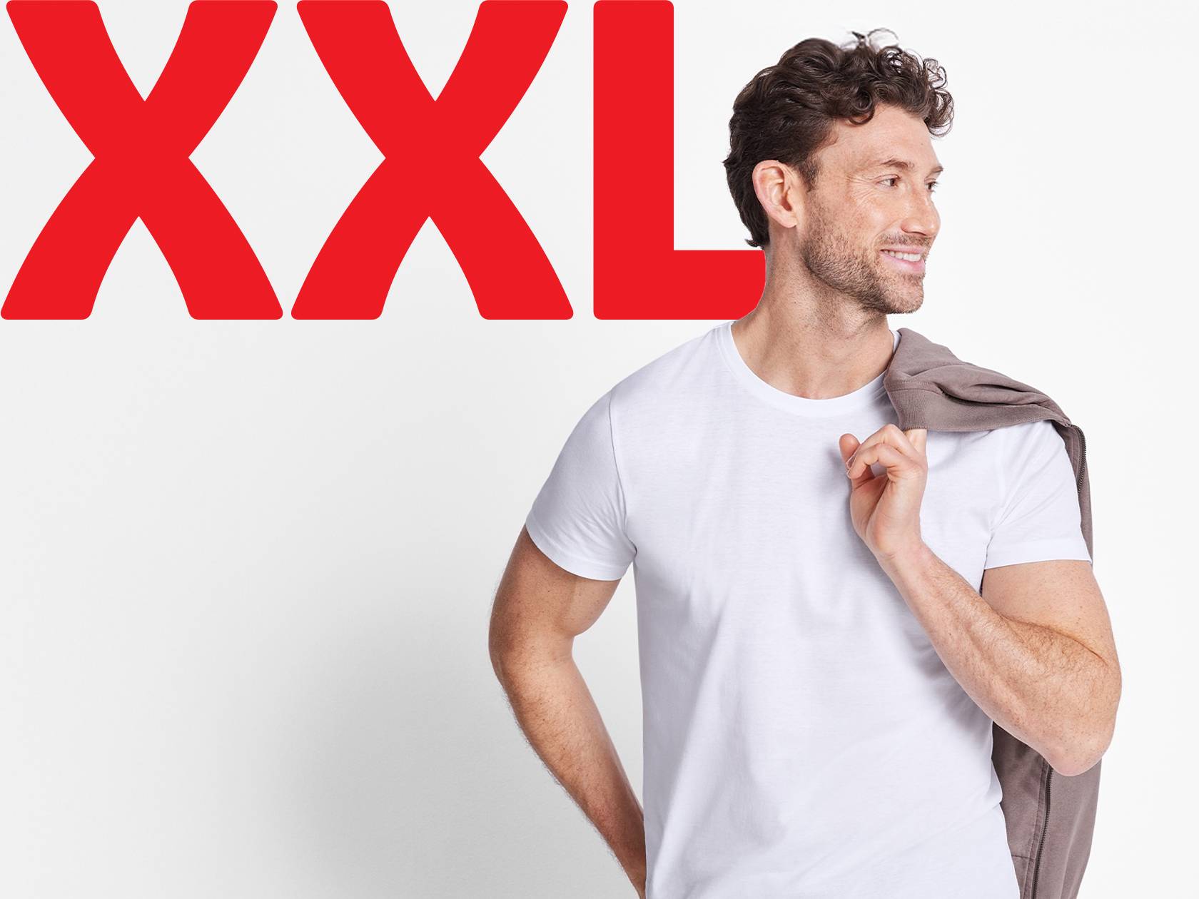 Vīrietis baltā XXL izmēra T-kreklā, uz pleca turot jaku.