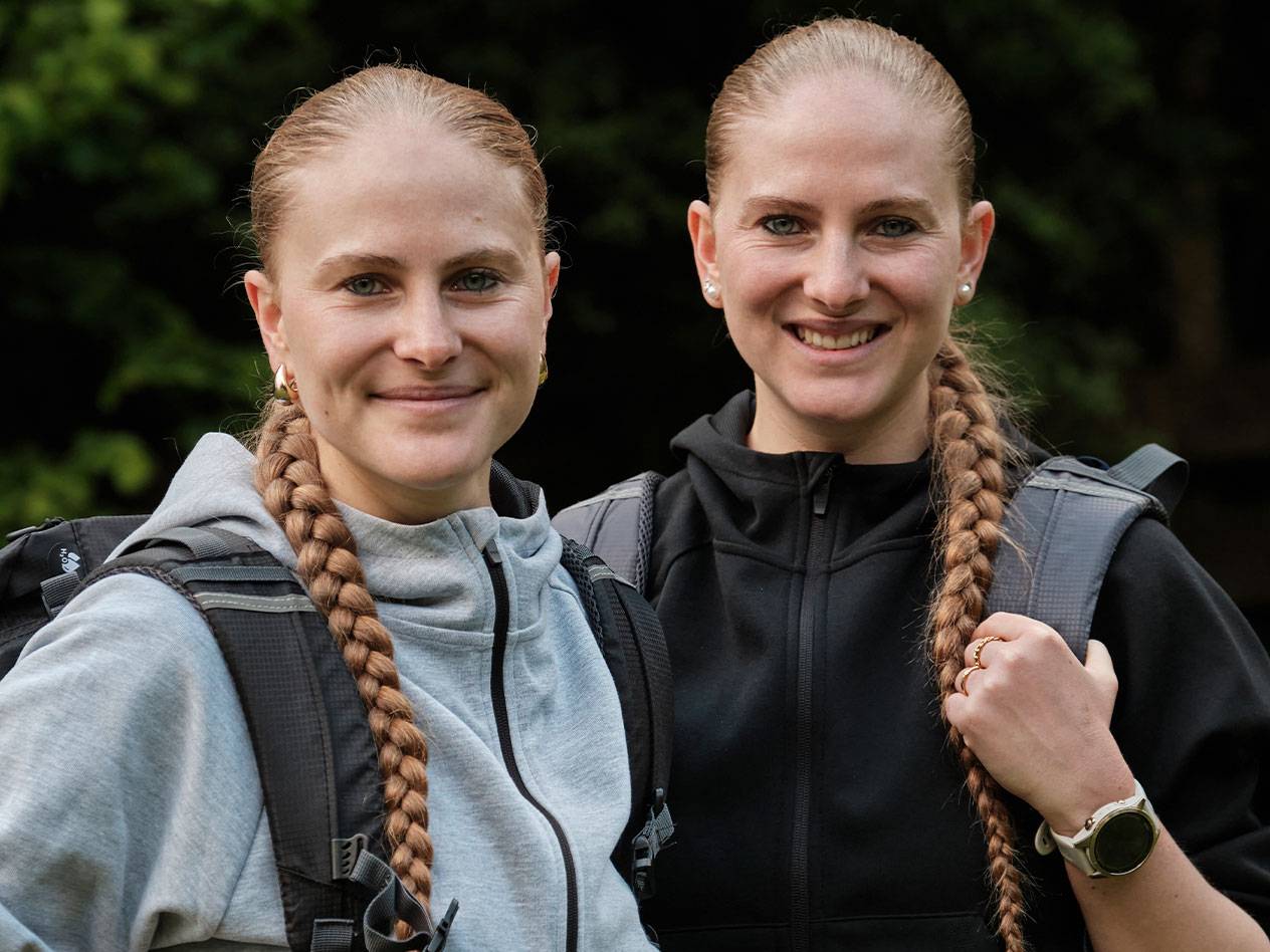 Divas sievietes ar mugursomām stāv kopā.