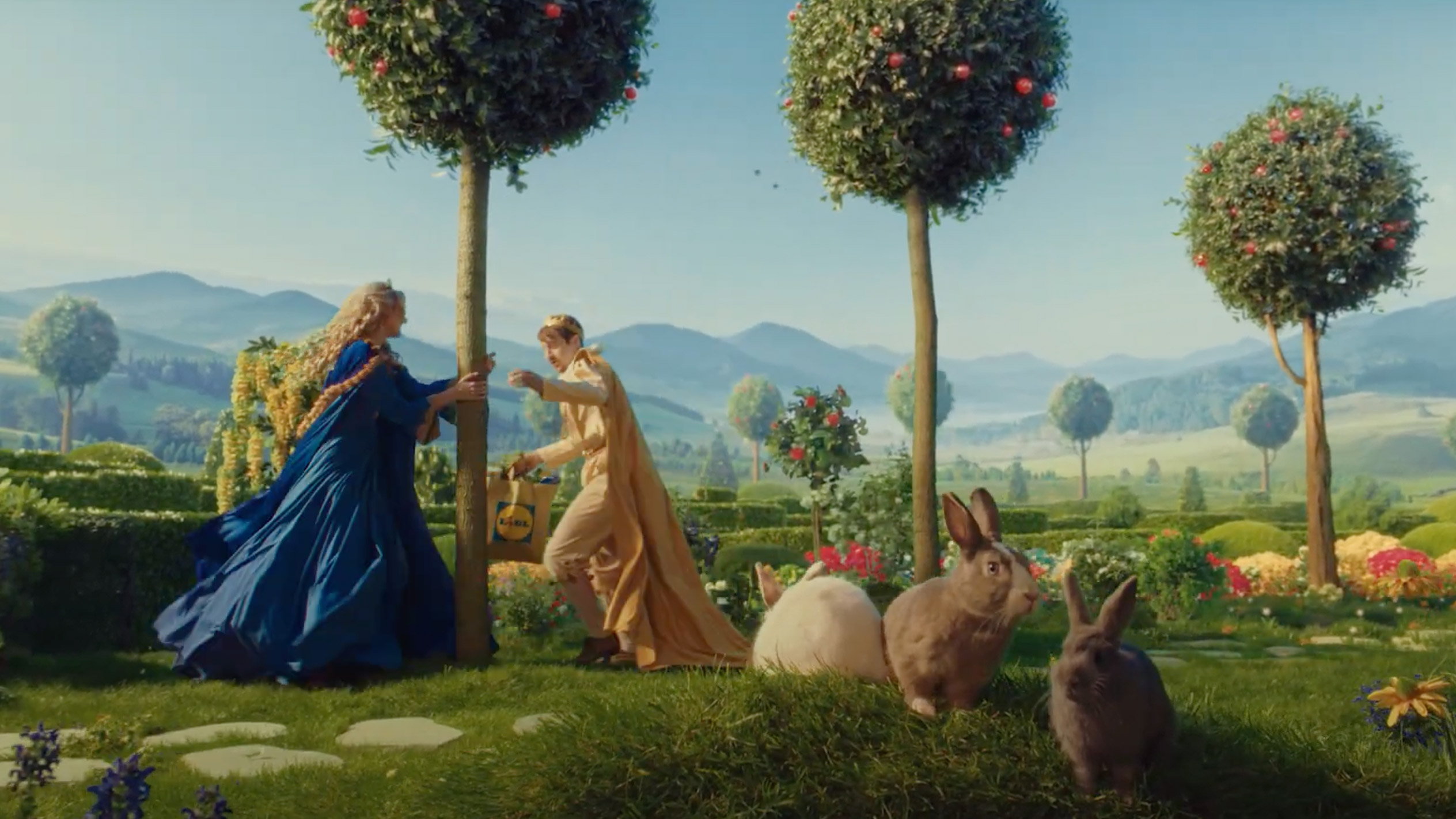 Lidl reklāmas video kadrs ar princesi un princim, kas iepērkās Lidl iepirkumu maisā.